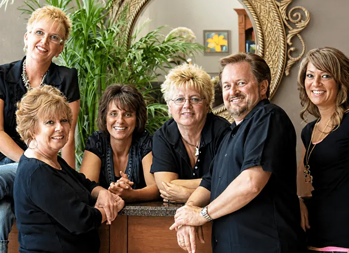 Group of six professionals posing together in a reception area, smiling at the camera.
