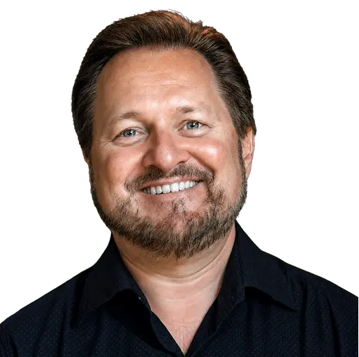 Portrait of a smiling man with short brown hair and a beard, wearing a dark button-down shirt, facing the camera.